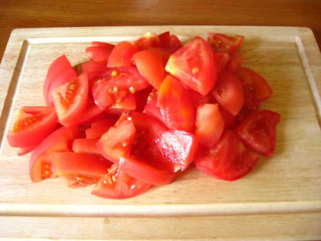 Нарізаний дольками помідор.