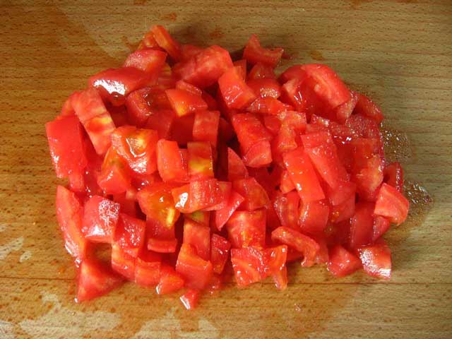 Очищений від шкірки і порізаний кубиками помідор.
