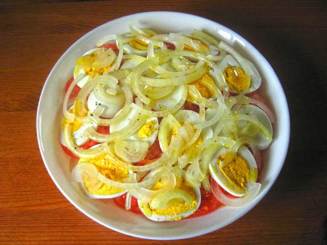 На яйця викладаємо шар цибулі і поливаємо салат заправкою. Салат з картоплі, яєць та помідорів готовий.