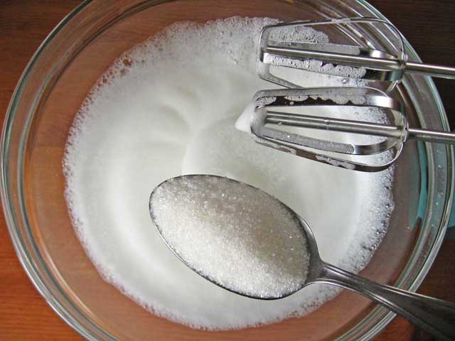 К слегка взбитым белкам добавляем сахар.