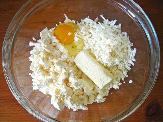 Бринза, кисломолочний сир, вершкове масло і яйце в посудині.