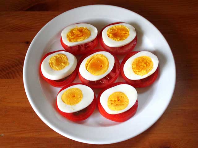 Выкладываем нарезанные яйца на помидоры.