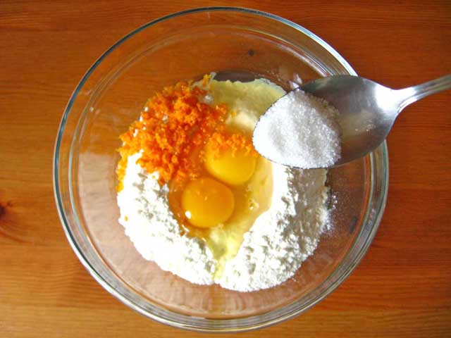 Кладем в емкость муку, яйца, цедру апельсина и добавляем сахар.
