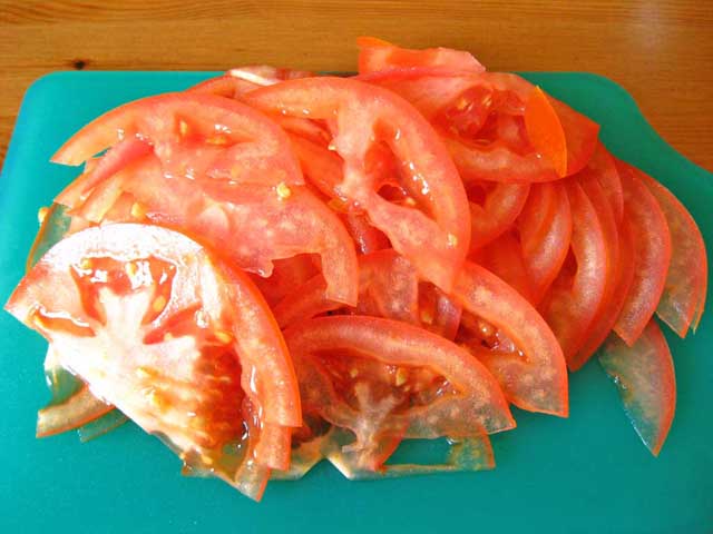 Нарезанные полукольцами помидоры.