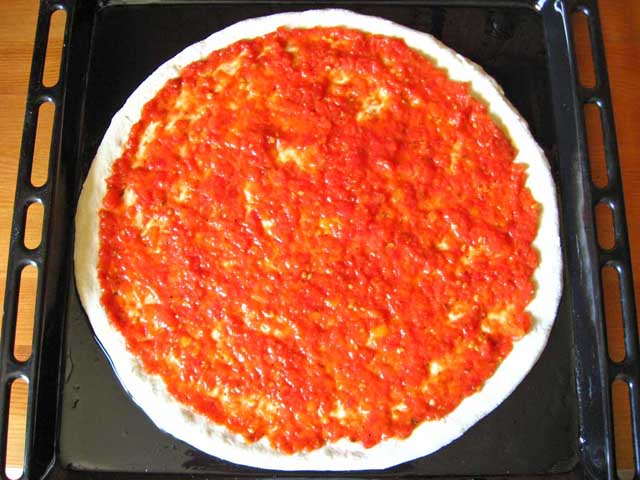 Равномерно выкладываем на тесто томатный соус для пиццы.
