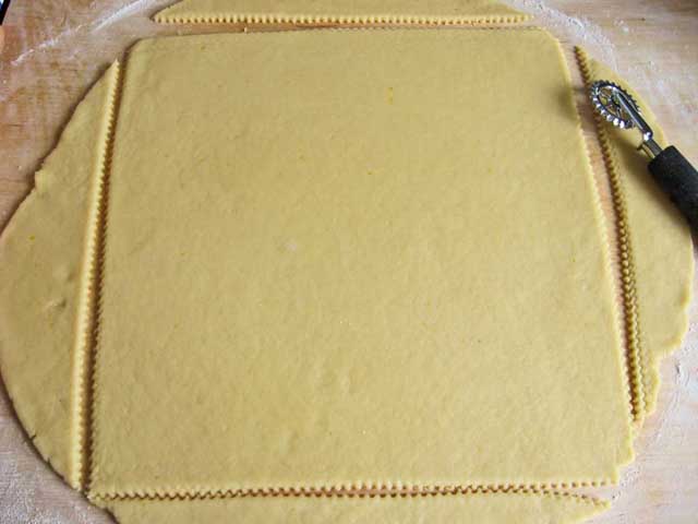 Раскатываем тесто и вырезаем его большим квадратом. Остатки слепляем вместе, ставим в пакет и в холодильник.