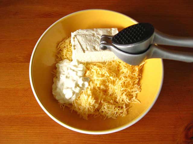 В посудину выкладываем сыр, сыр, сметану и выдавливаем чеснок. Перемешиваем.